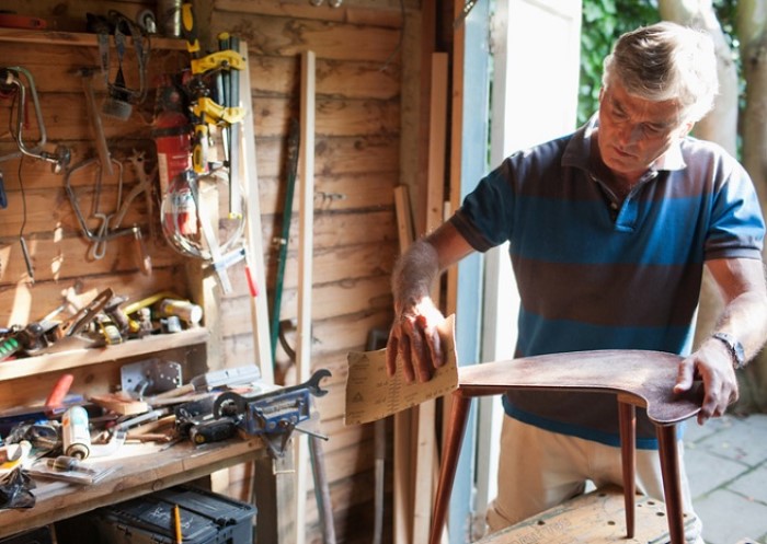 Mann schmirgelt Holz in Workshop