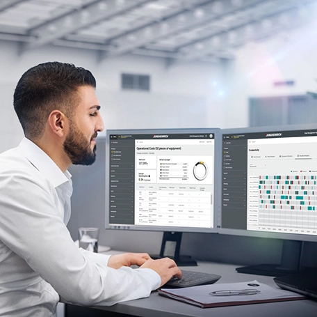 Een kantoormedewerker houdt op de pc toezicht op de geïmplementeerde nieuwe magazijnplanning en optimaliseert deze